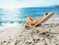 Girl tans on a deck chair on a beautiful beach Royalty Free Stock Photo