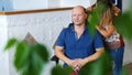 A girl, tattoo master, mehendi artist makes drawing of henna tattoo on the scalp of bald Caucasian man , in a blue shirt Royalty Free Stock Photo