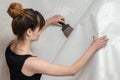 The girl tears off the old wallpaper from the concrete wall and holds a spatula. Royalty Free Stock Photo