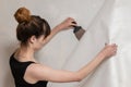 The girl tears off the old wallpaper from the concrete wall and holds a spatula. Royalty Free Stock Photo