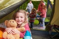 Girl With Teddy Bear Enjoying Camping Holiday On Campsite