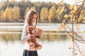 Girl with teddy bear holds dry leaf on riverbank in forest Royalty Free Stock Photo