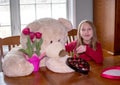 Girl and teddy bear share valentines day gifts