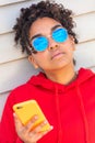 African American female young woman wearing blue sunglasses using cell phone Royalty Free Stock Photo