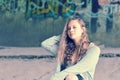 Girl teenager with flowing brown hair sitting against concrete w Royalty Free Stock Photo
