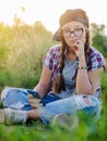 Girl teenager in glasses sits the ground city background in the headphones of selfie smartphone