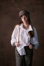 Girl teenager in a hat with a visor in a white shirt and trousers. studio brown background, fashion