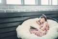 Girl teenager in a pink dress sitting in a chair on a white fur plaid and reading a book. Royalty Free Stock Photo