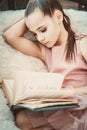 Girl teenager in a pink dress sitting in a chairand reading a book. Royalty Free Stock Photo