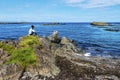 Girl teenager is siting in the border of Hunar Bay looking at wild landscape of western shore of Vatnsnes peninsula in Northwest Royalty Free Stock Photo