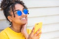Girl teenager teen female young African American woman wearing sunglasses using cell phone Royalty Free Stock Photo