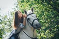 Girl teenager and white horse in a park in a summer Royalty Free Stock Photo