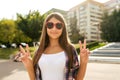 Girl teenager 9-13 years old, standing in summer in city park, hand gesture hello victory. In the summer, happy smiles Royalty Free Stock Photo