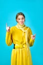 Girl teenager in yellow clothes makes gesture with her fingers. blue background