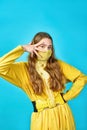 Girl teenager in yellow mask on her face makes gesture with her fingers. blue background