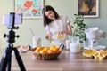 Girl teenager young food blogger cooking orange pancakes, pours orange juice