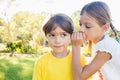 Girl telling a secret in the ear of a little boy in a park Royalty Free Stock Photo