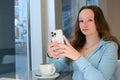 Girl texting on the smart phone in a restaurant terrace with an unfocused background Royalty Free Stock Photo