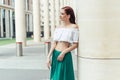 A girl of thirty with red hair next to a fancy building in the summertime