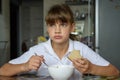 Girl thoughtfully eats soup at the table in the kitchen