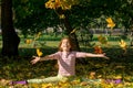 Girl throw yellow leaves up in autumn in the park.