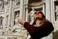 Girl throwing coin in famous Trevi Fountain in Rome, Italy.