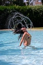 Girl throwing hair back fast in sunny, blue swimming pool Royalty Free Stock Photo