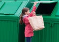 Girl throws out a paper bag opening the trash container