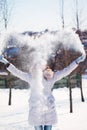 The girl throws snow in the frosty winter afternoon