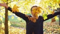 Girl throws up leaves and smiling in autumn park