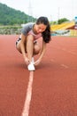 Girl tightening shoelaces on a jogging track