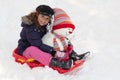 Girl with toboggan and snowman Royalty Free Stock Photo