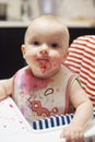 Playing with food and learning to eat concept. Dirty face of happy kid. Portrait of a baby eating with a stained face. Royalty Free Stock Photo