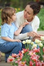 Girl together with mother sits at bed with tulips Royalty Free Stock Photo