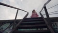 The girl on top of the metal stairs makes a pathos, epic movement for the clip