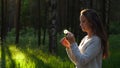 Woman touch fingers flower on dandelion seed head, blow and floret fly away