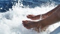 Girl touches the feet of a wave, a background of blue sea water Royalty Free Stock Photo