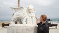 The girl touches the sculpture of a lion on the waterfront of Larnaca in Cyprus