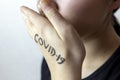 Girl touching face with hands with covid-19 written on it.