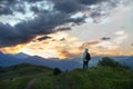 A girl tourist admires the sunset in the mountains. Silhouettes of mountains against the background of the sunset sky