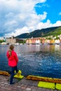 Girl tourist on the background of the sea bay and old wooden houses on the embankment of Bergen