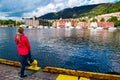 Girl tourist on the background of the sea bay and old wooden houses on the embankment of Bergen