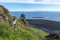 Girl tourist looking at Hvitserkur basalt stack washed with waters of Hindisvik bay in Northwest Iceland