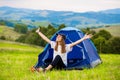 Girl tourist meets morning with outstretched arms in tent with beautiful mountains view. Royalty Free Stock Photo