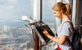 Girl tourist with monitor of computer at window of skyscraper Royalty Free Stock Photo