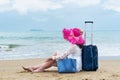 Girl tourist sits on the beach with luggage bag
