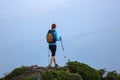 The girl with the touristic equipment goes up to the peak of the rocky high hill with the lawn. The scenery of the mountain. Royalty Free Stock Photo