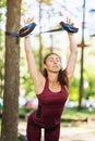 Girl in a tracksuit is doing exercises in a city park using a suspension trainer