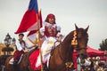 Girl in traditional costume with flag rides a horse