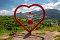 Girl in traditional costume posing with red wooden heart in village Terchova at Slovakia